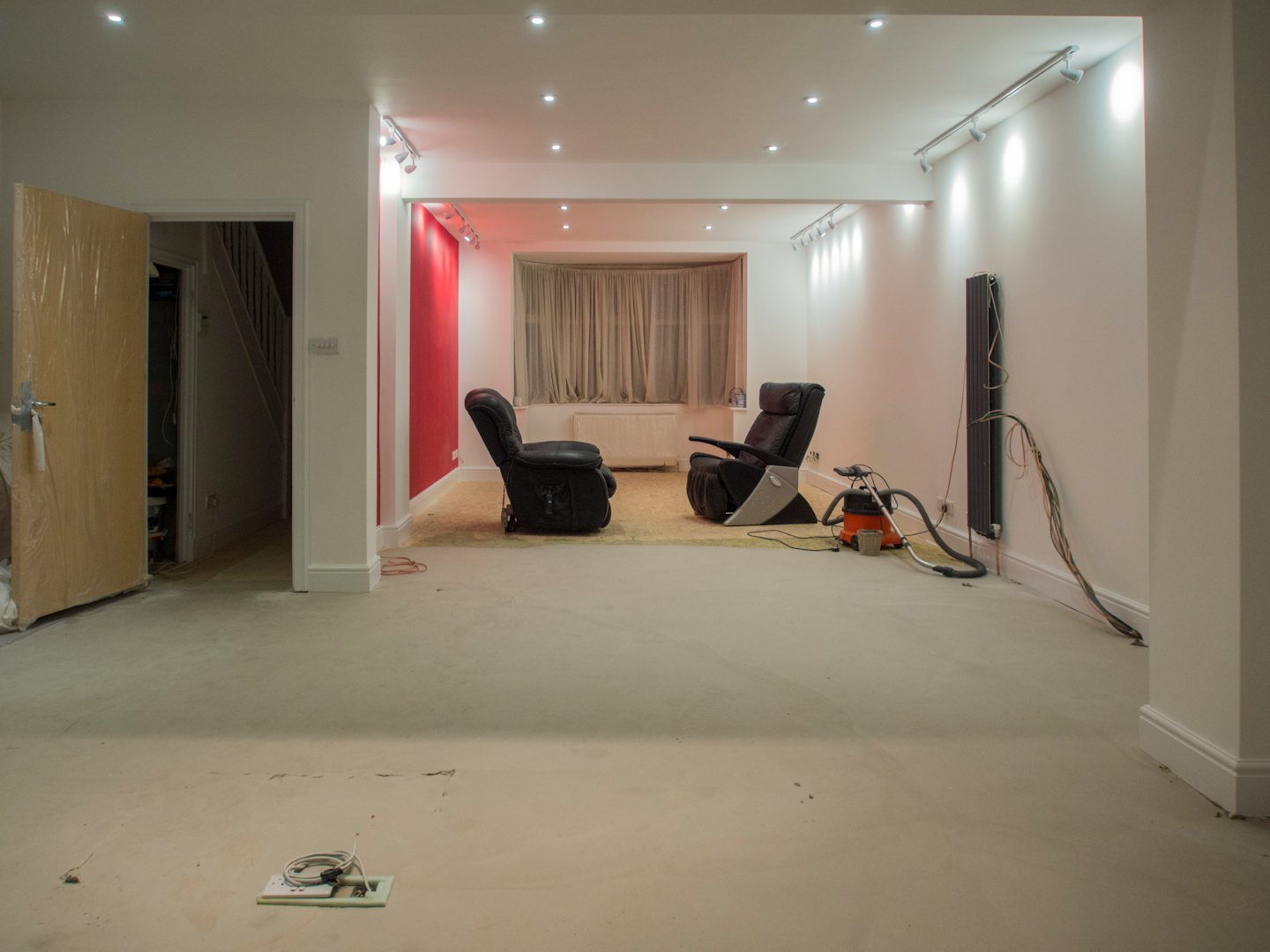 Living room undergoing renovations with tools and exposed wiring.