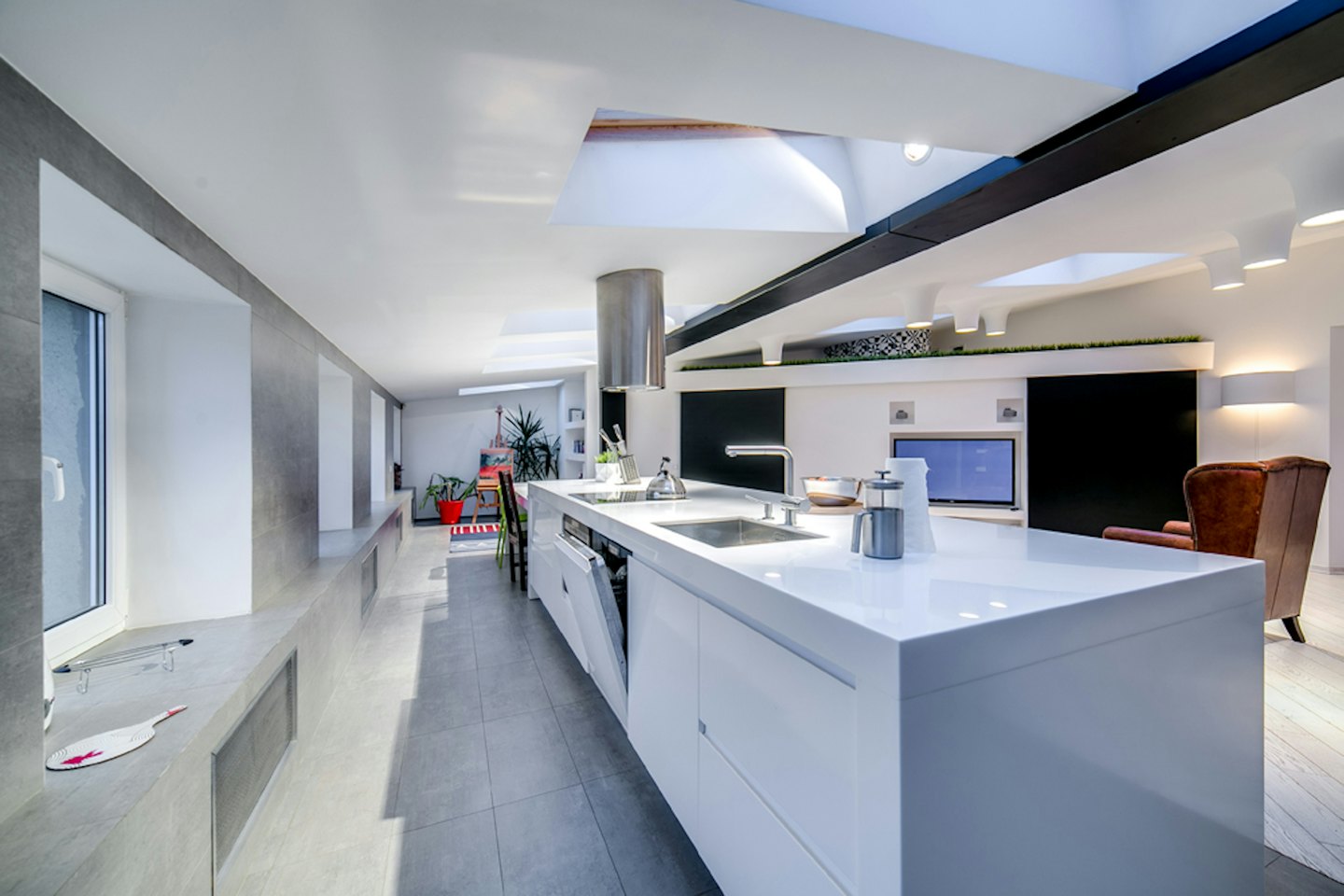 Modern open kitchen with a white island and leather armchair.